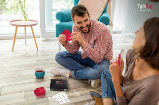 Playful couple sitting on the floor playing a relationship card game