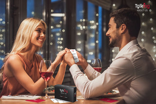 Couple sitting together playing Conversations About Us Intimacy & Passion card game for couples on a dinner date.