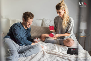 Playful couple sitting in bed playing a relationship card game