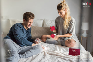 Playful couple sitting in bed playing a relationship card game
